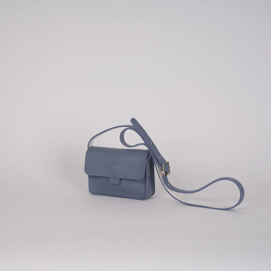 Blue handbag with a strap on a light gray background