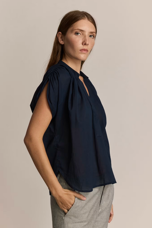 Woman wearing a dark blue blouse with a plain background