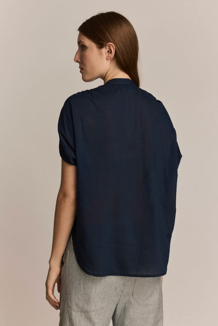 Person wearing a navy blue shirt against a beige background. Back view