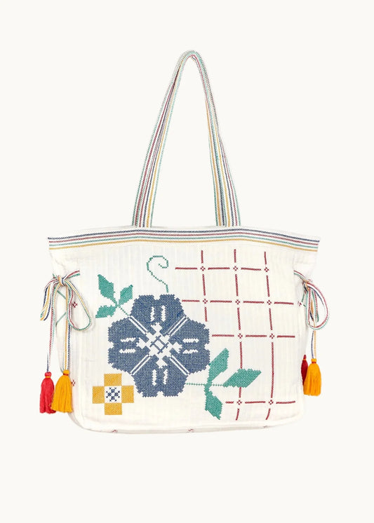 White tote bag with floral embroidery and colorful tassels on a white background