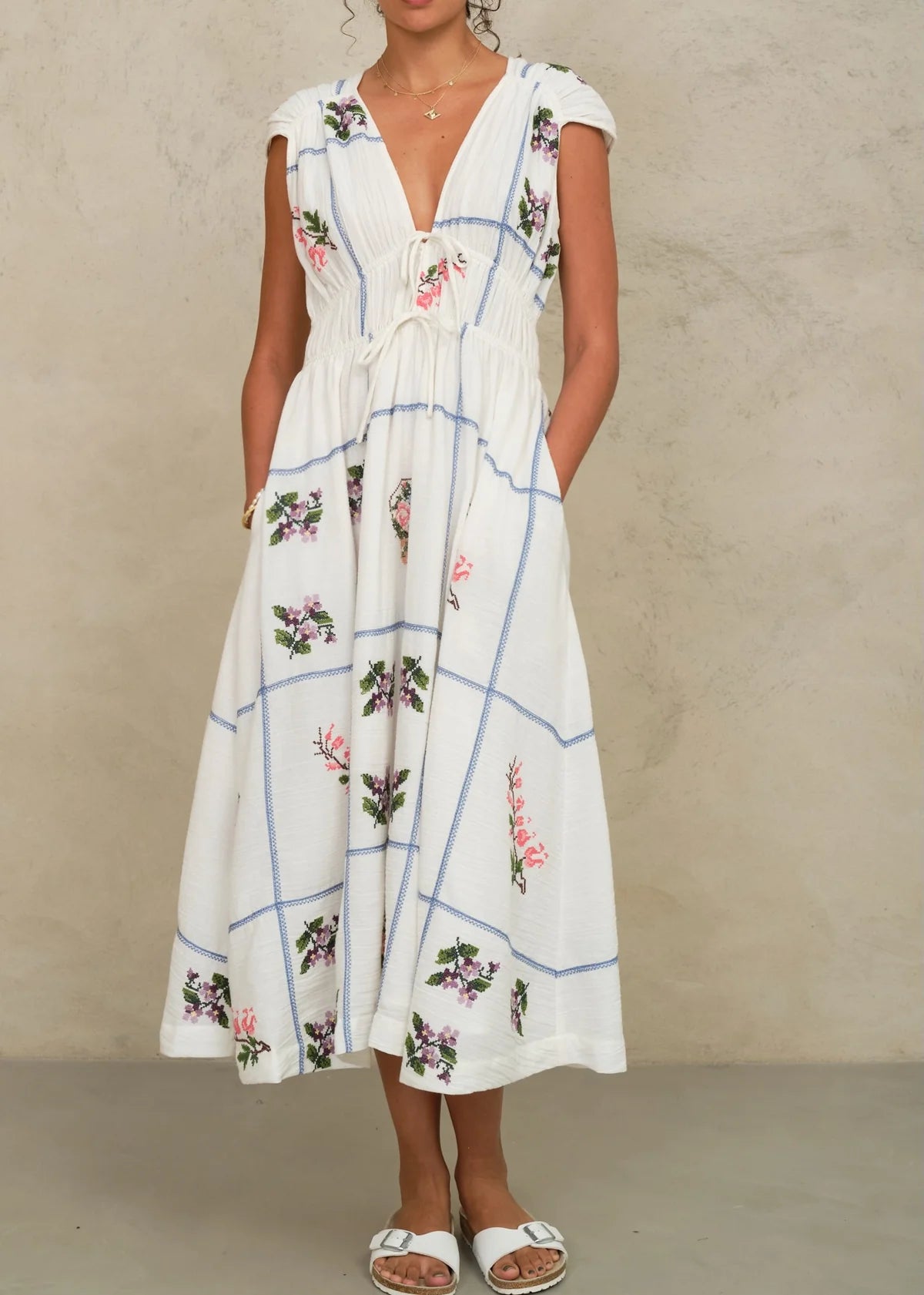 Woman wearing a white floral dress against a beige background