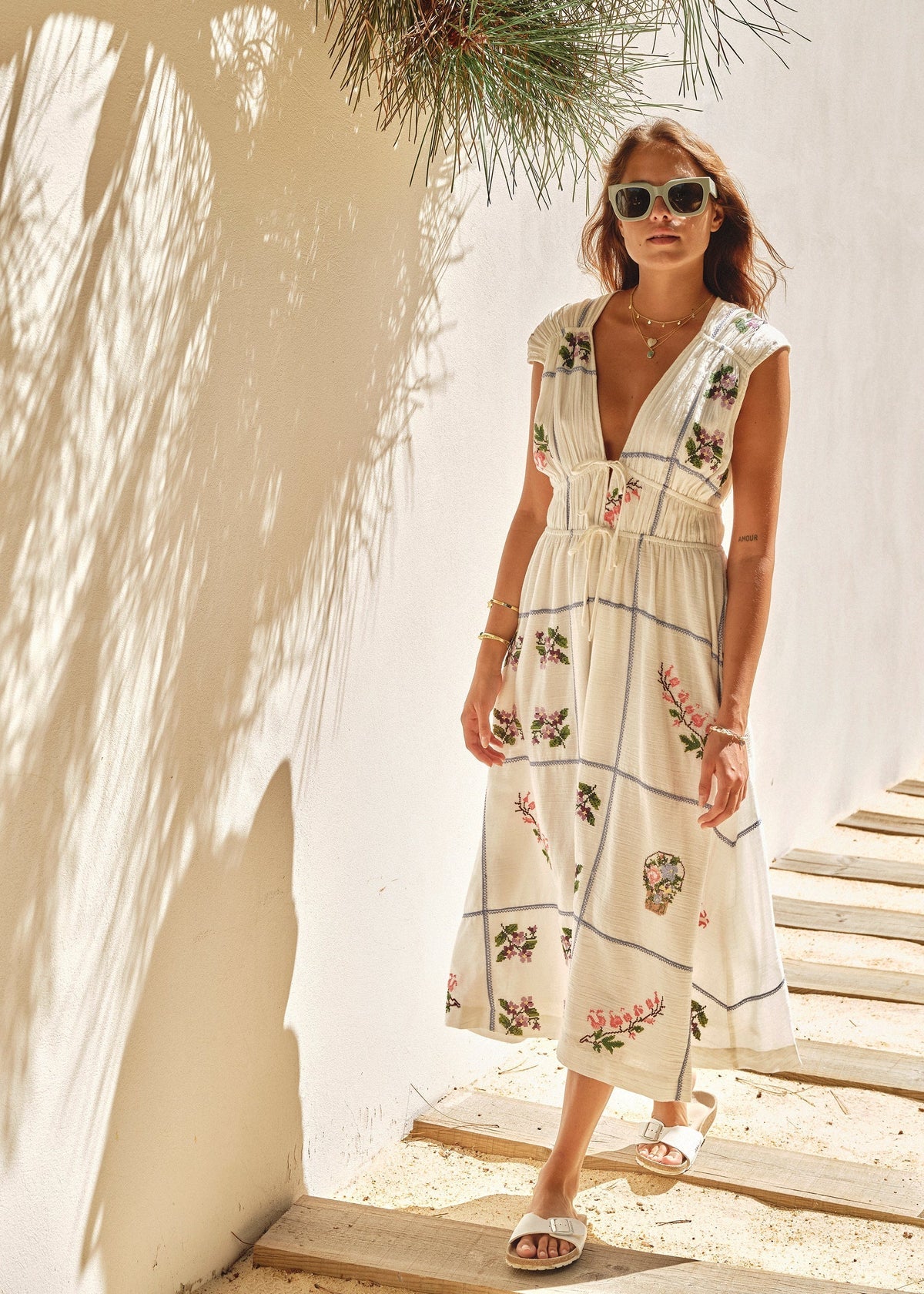 Woman in a floral dress standing under a palm tree