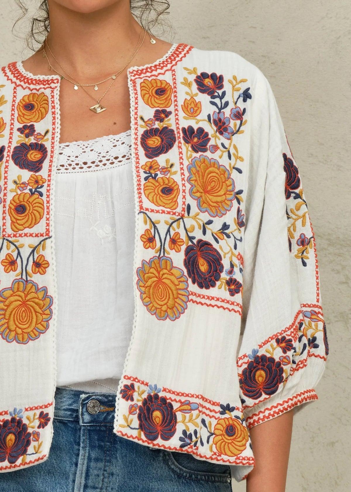 White embroidered jacket with colorful floral patterns worn by a person.
