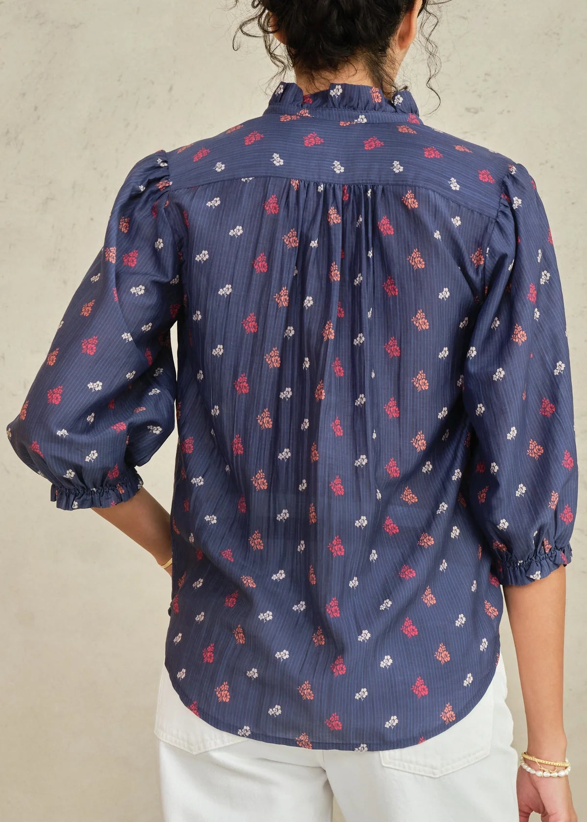 Person wearing a navy blue patterned shirt against a neutral background