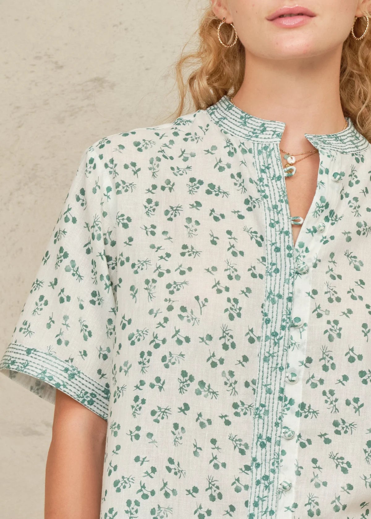 Close-up of a person wearing a floral patterned shirt against a neutral background