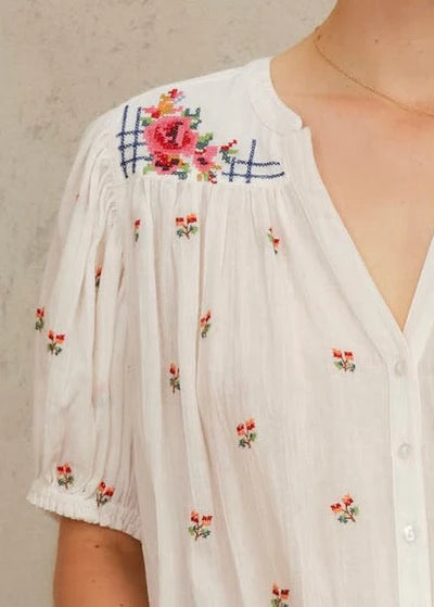 White blouse with floral embroidery on a neutral background