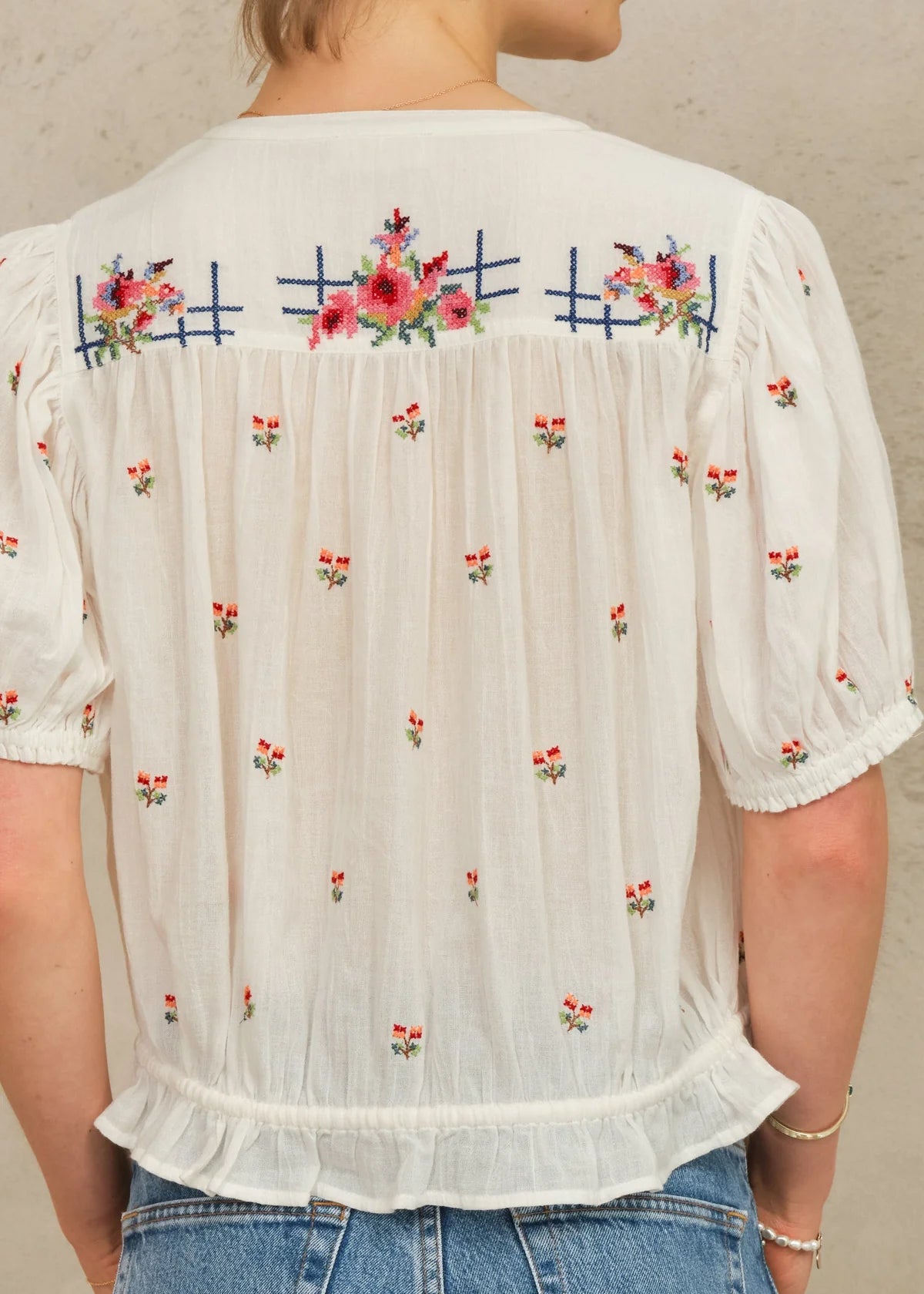 White blouse with floral embroidery on a plain background