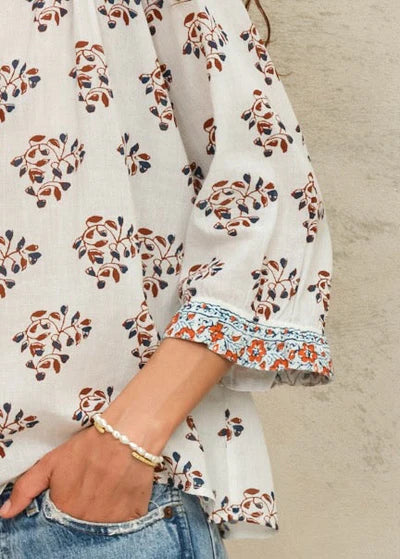 Floral patterned blouse with bell sleeves and a sand-colored background