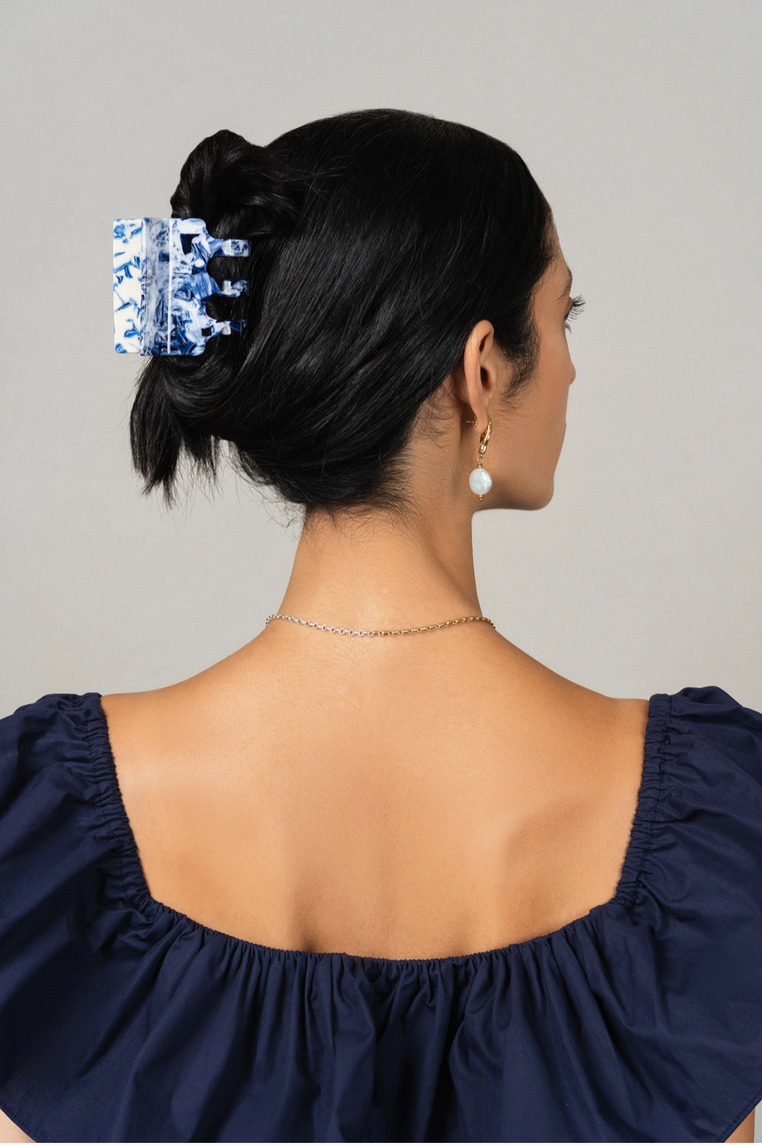 photo of woman taken from behind with long black hair wearing a blue and white hair claw