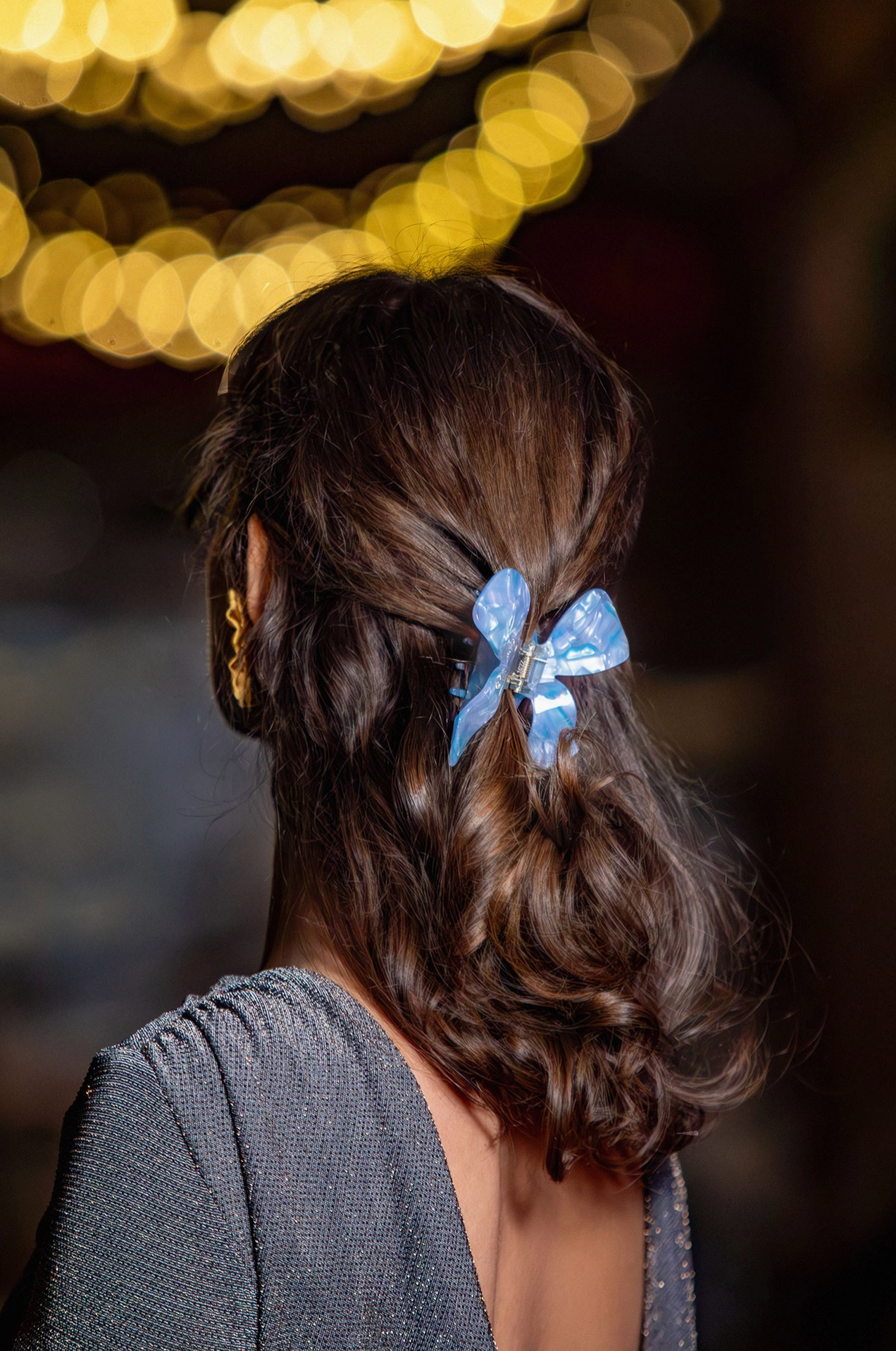 Rear view of woman with long brown hair wearing blue bow shaped hair claw