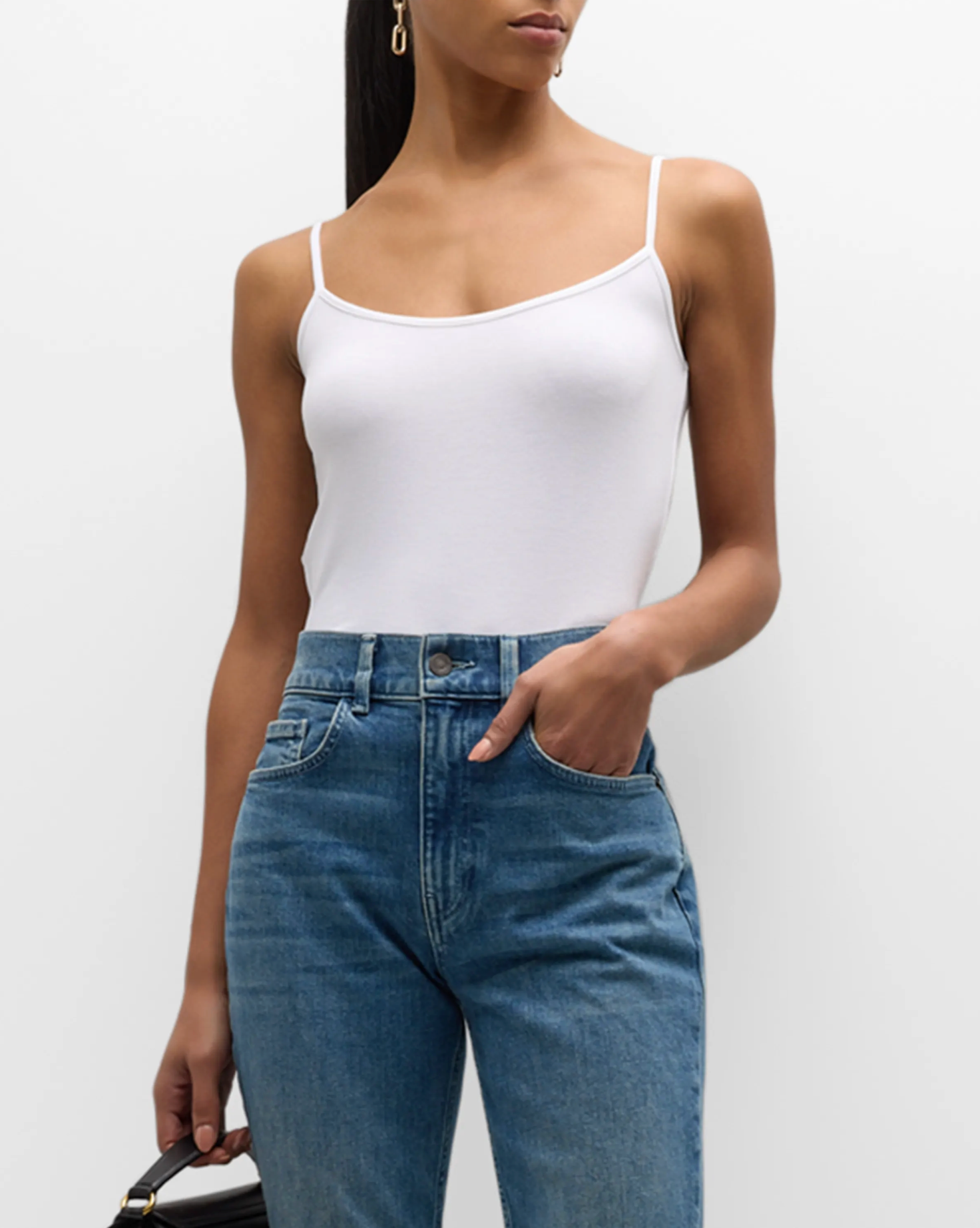 Person wearing a white tank top and blue jeans on a plain background