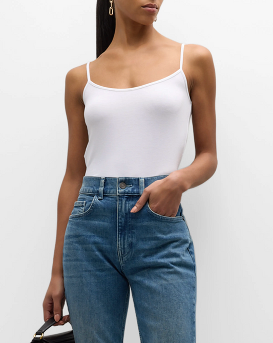 Person wearing a white tank top and blue jeans on a plain background