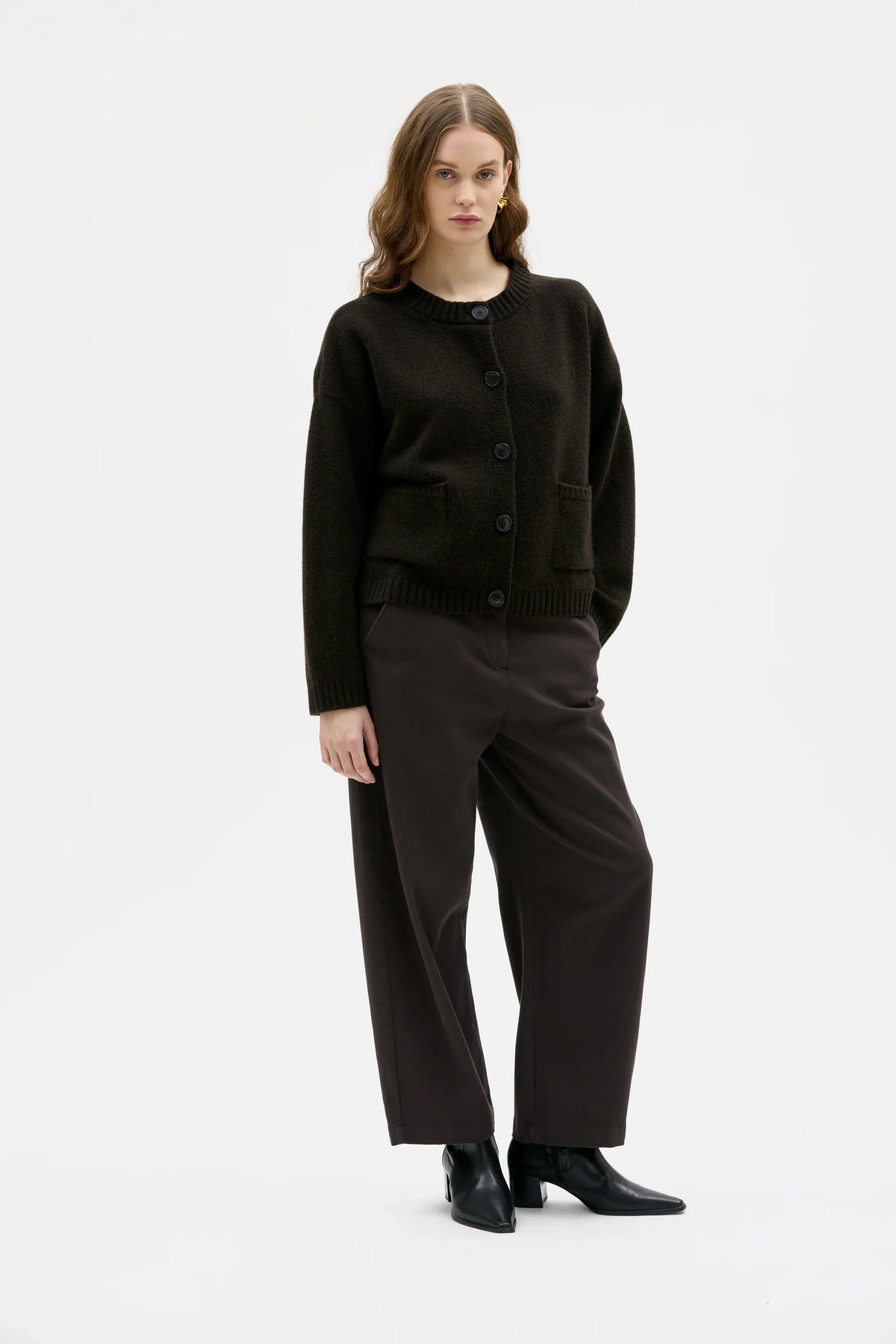 Woman wearing a brown sweater and black pants on a white background