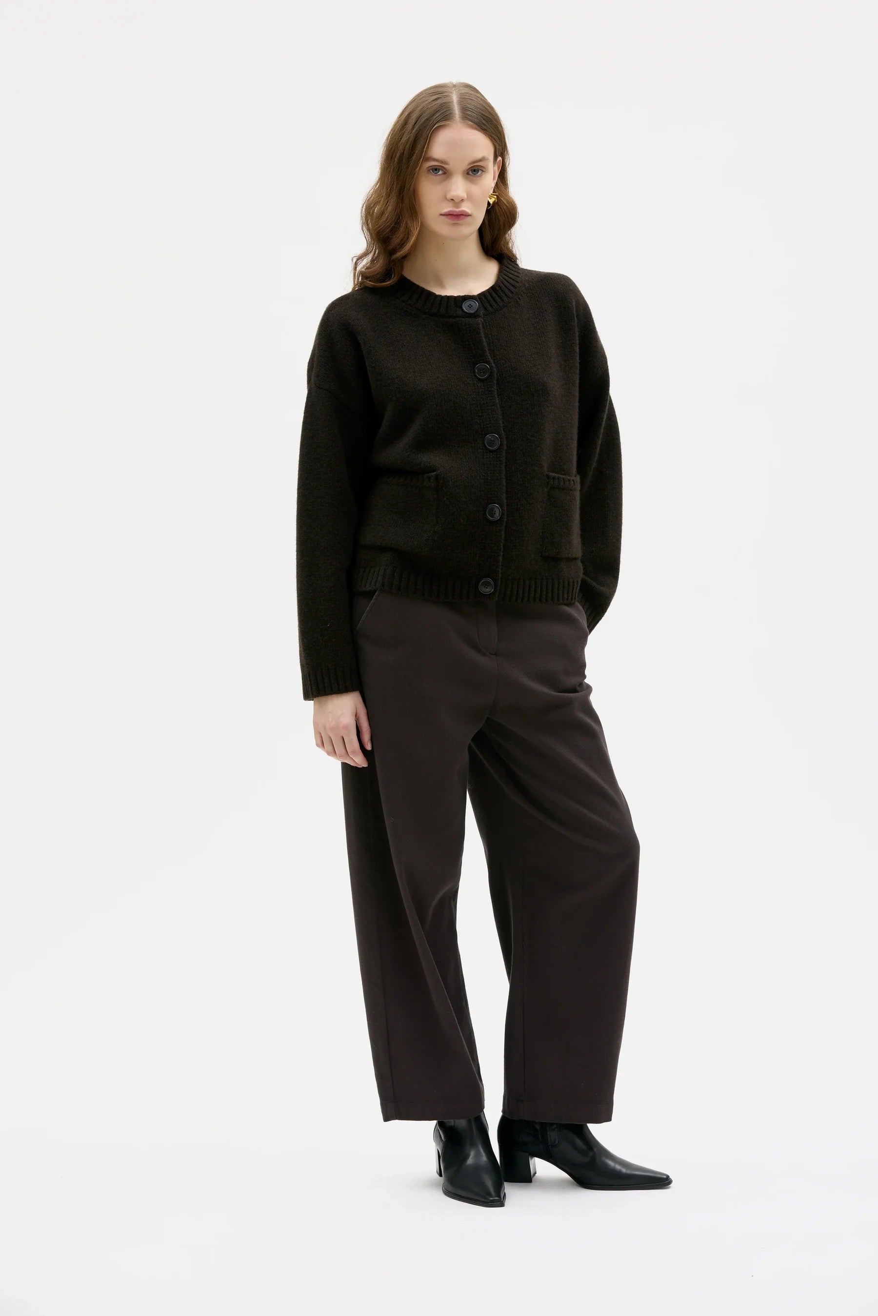 Woman wearing a brown sweater and black pants on a white background