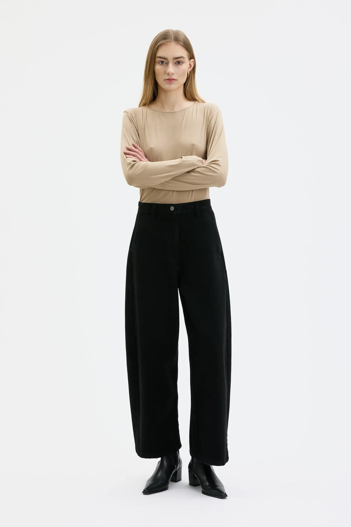 Woman wearing a beige sweater and black pants on a white background