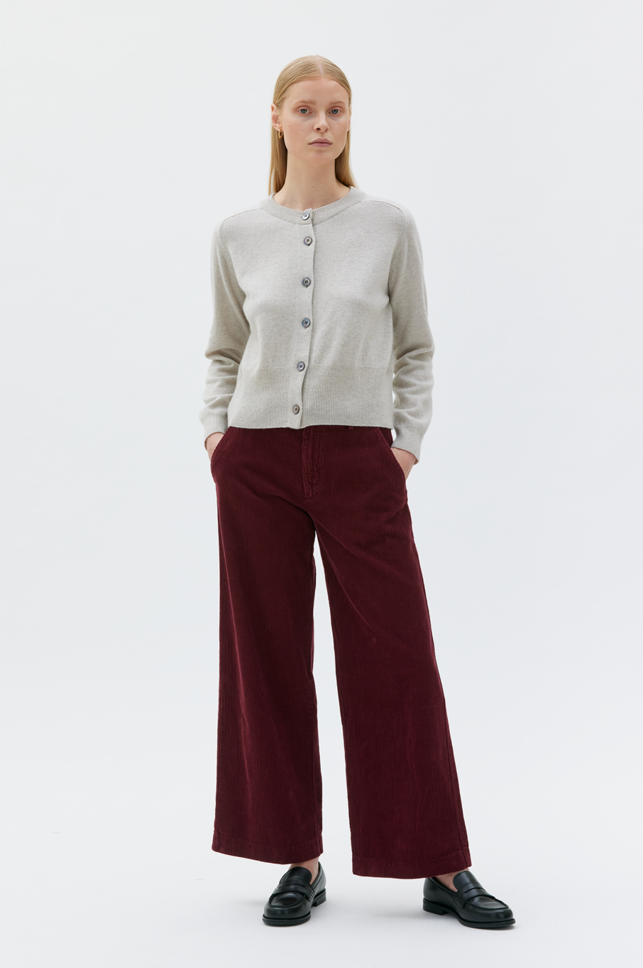 Woman wearing sand colored cropped cardigan with burgundy pants