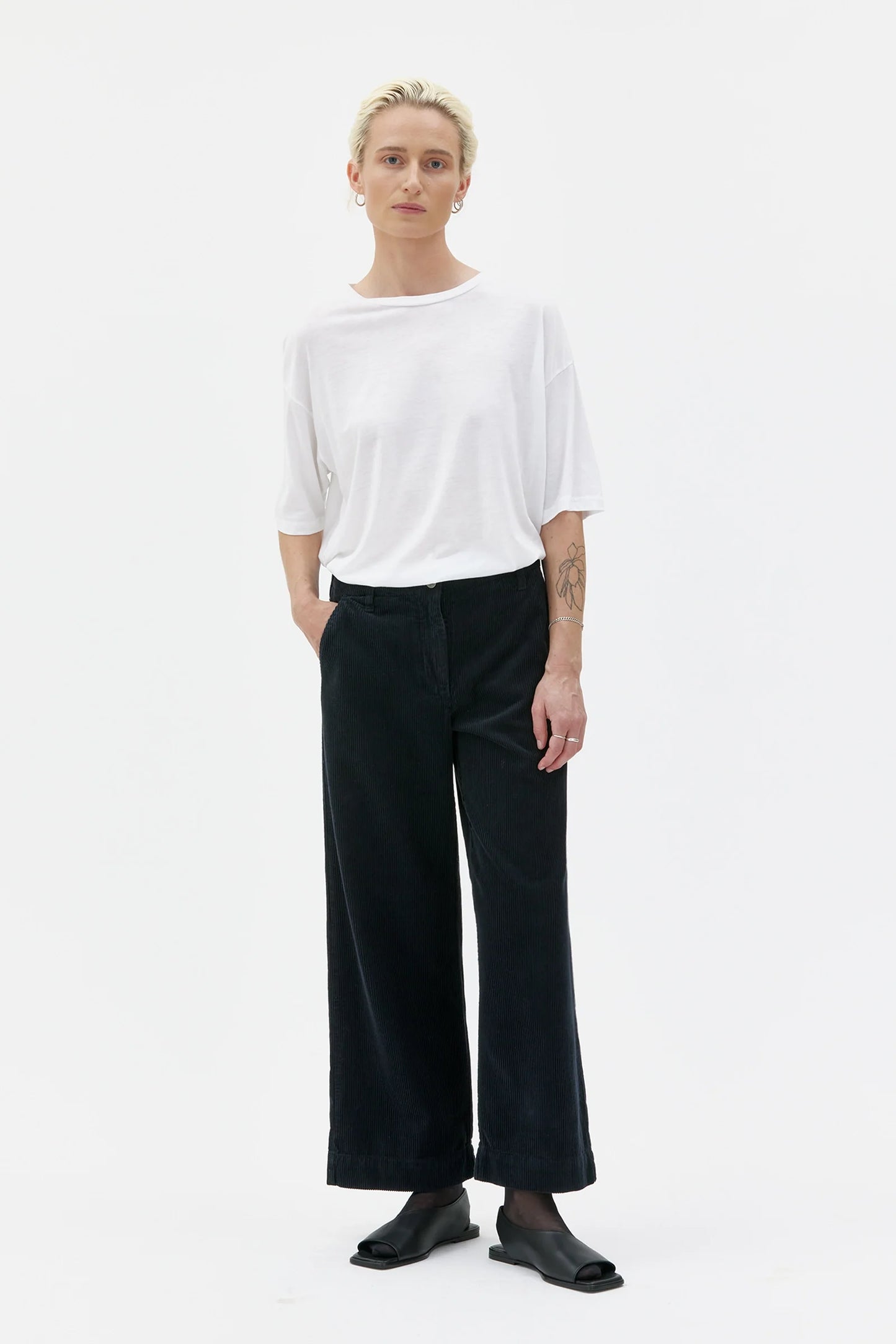 Person wearing a white top and black pants on a white background