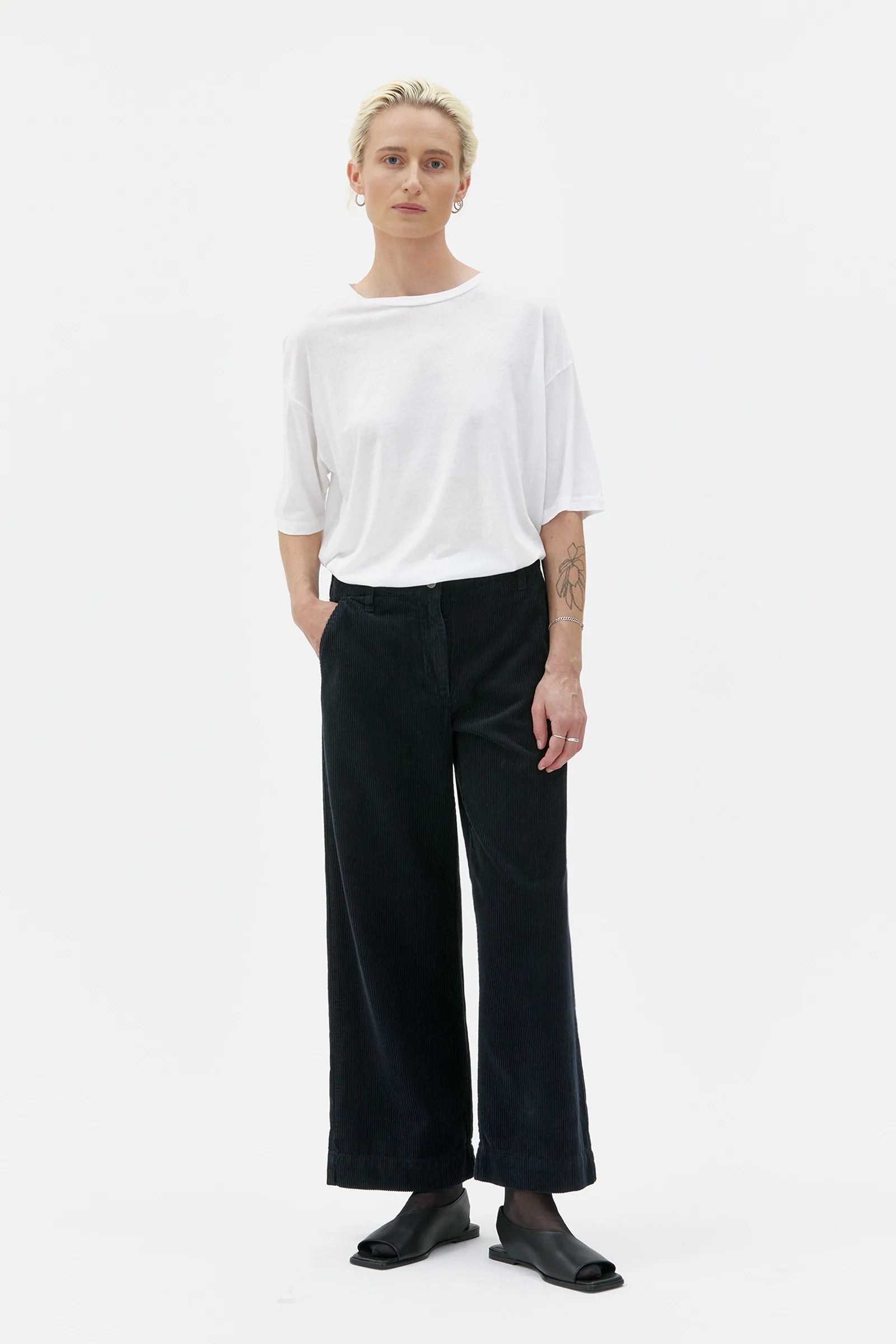 Person wearing a white top and black pants on a white background