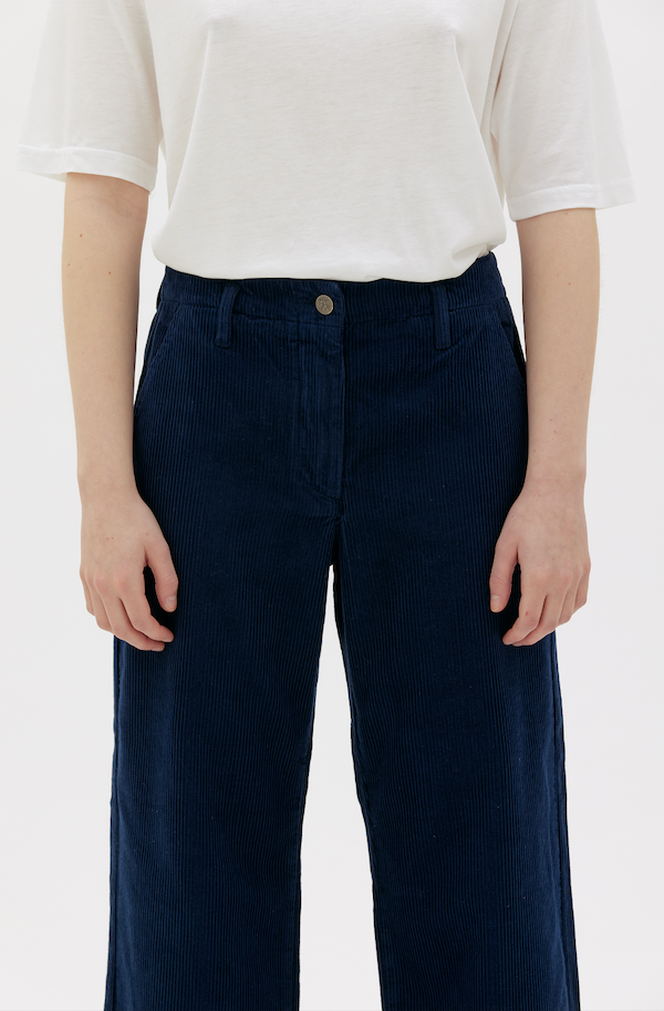 cropped detail of woman wearing royal blue corduroy pants with white t-shirt