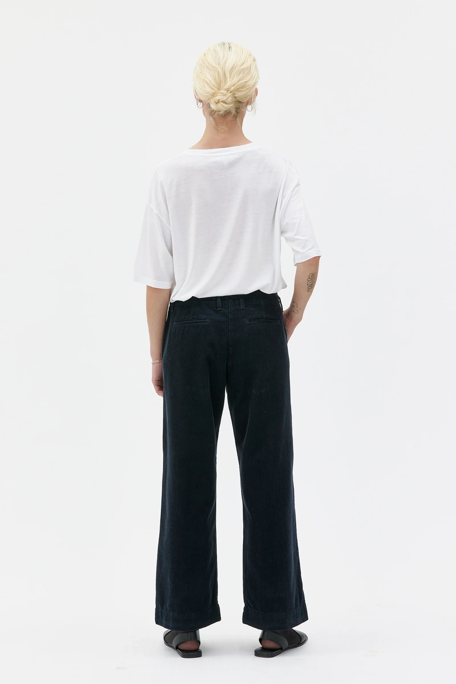 Person wearing a white shirt and black pants on a white background