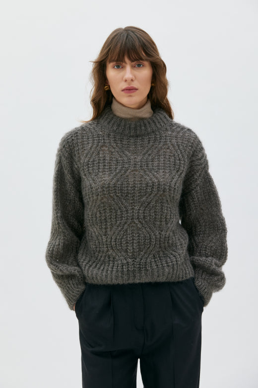 Person wearing a textured gray sweater against a plain background