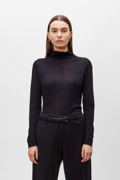 Person wearing a black turtleneck and black pants on a white background