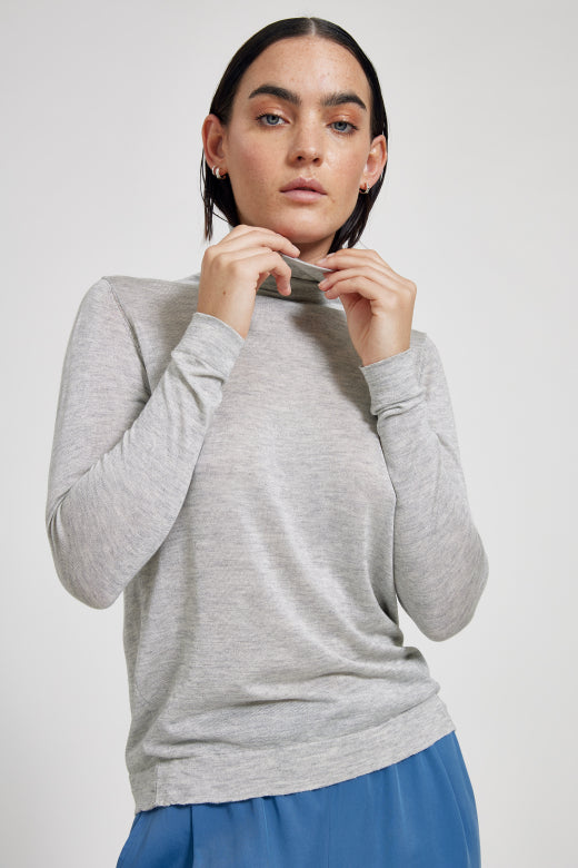 Woman wearing a gray long-sleeve top against a white background