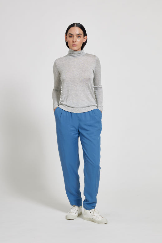 Person wearing a gray turtleneck and blue pants on a white background