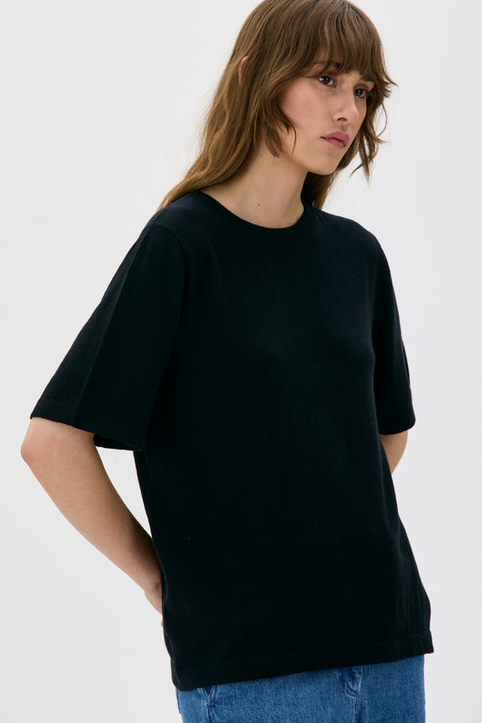 Person wearing a black t-shirt and blue jeans on a white background