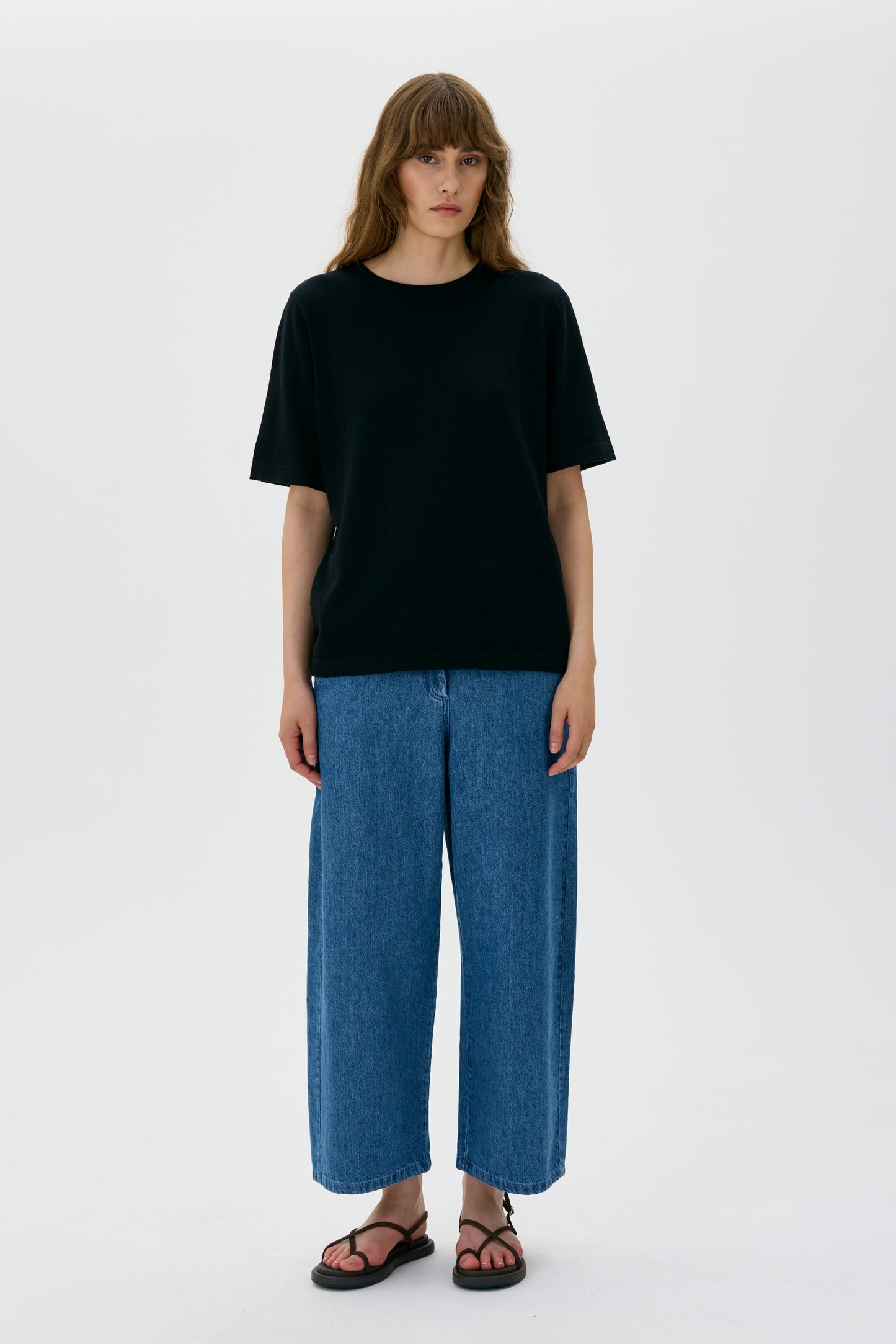 Person wearing a black t-shirt and blue jeans on a white background