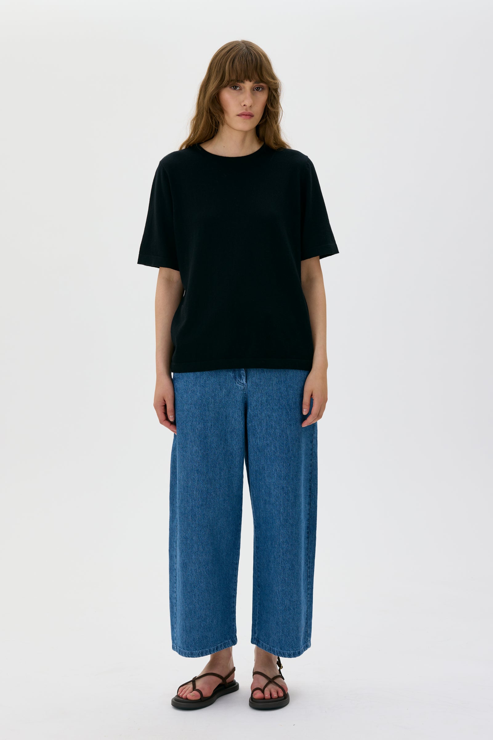Person wearing a black t-shirt and blue jeans on a white background