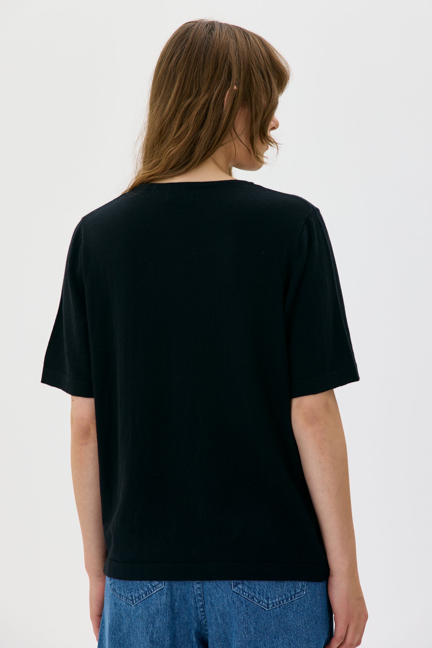 Person wearing a black t-shirt and blue jeans on a white background
