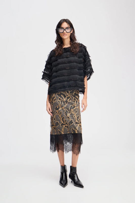 Woman wearing a black top and patterned skirt on a white background