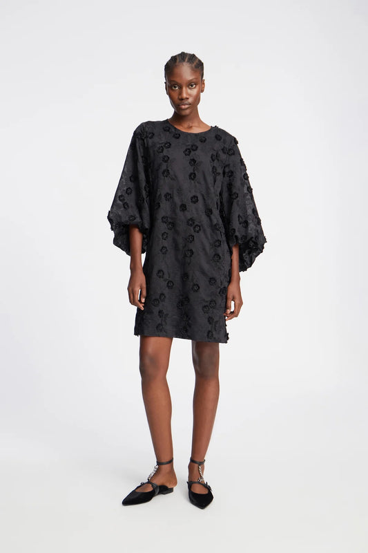 Picture of young women with dark skin brown eyes wearing a black dress.
