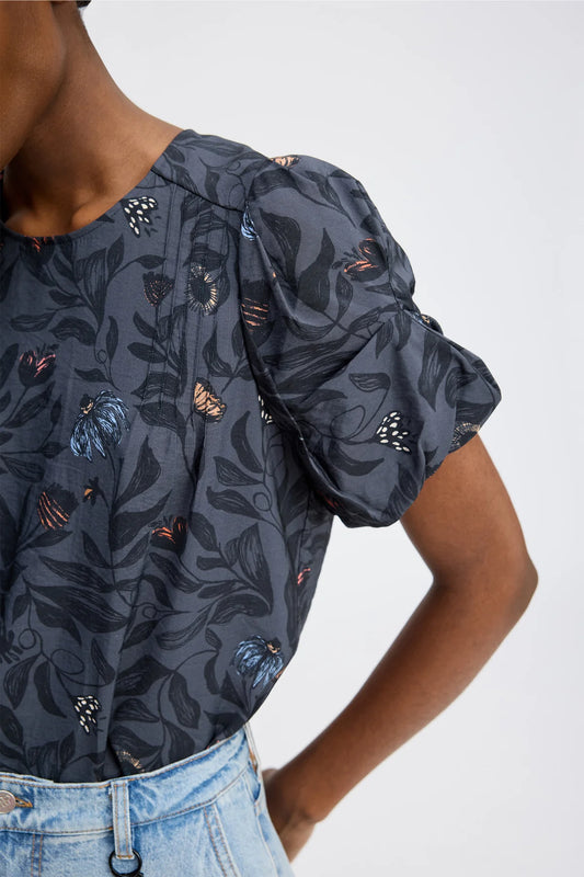 Dark floral patterned top worn by a person on a white background
