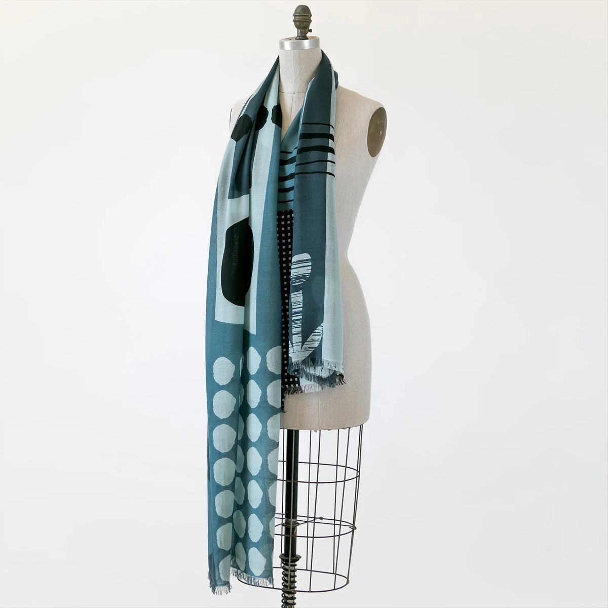 A long blue scarf in a playful pattern shown wrapped around a mannequin.