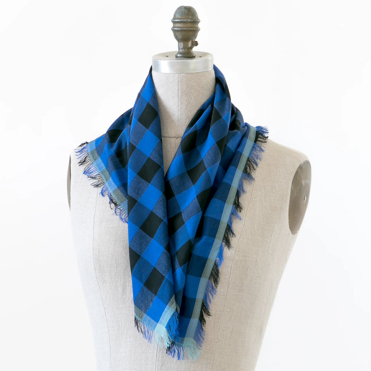 A small blue and black checkered gingham scarf shown wrapped around a mannequin.