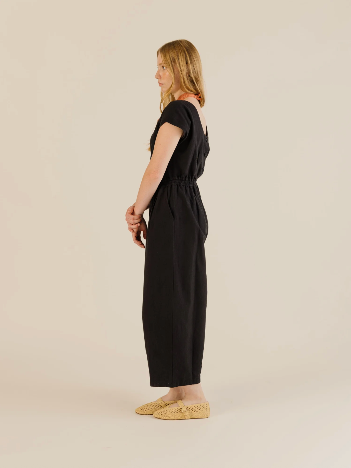 Woman wearing a black jumpsuit on a beige background