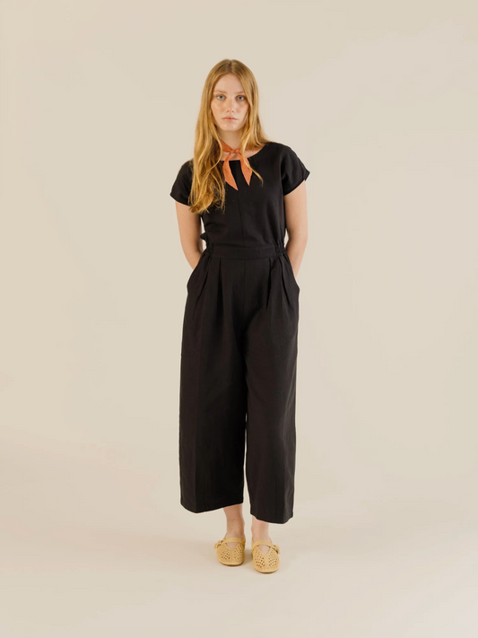 Woman wearing a black jumpsuit on a beige background