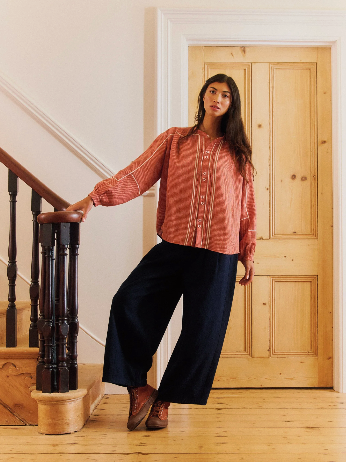 Woman standing in a room with wooden door and staircase