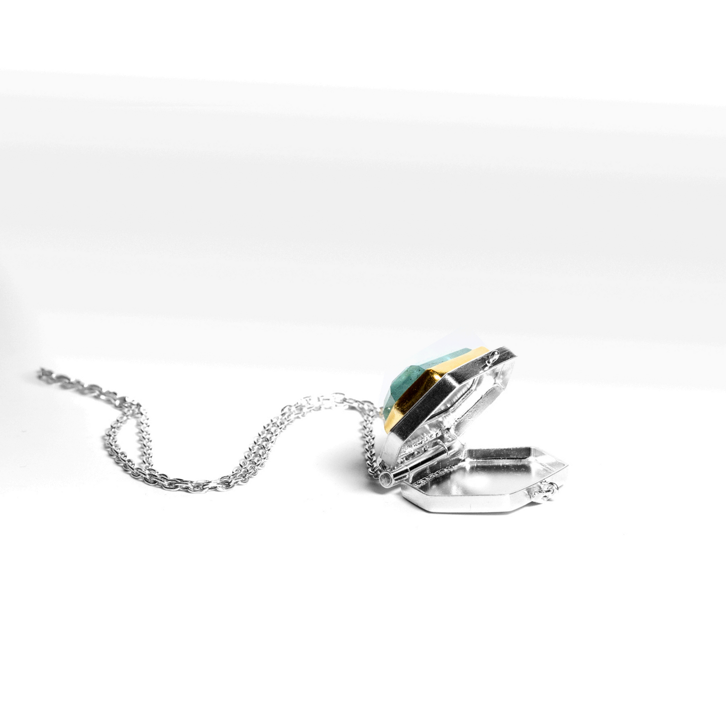 Hexagonal locket necklace with hexagonal aquamarine and chain on a white background photographed in open position