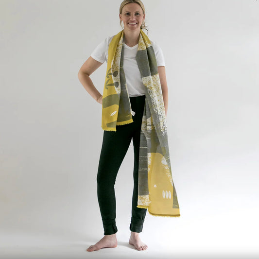 Woman wearing a long, patterned scarf on a plain background