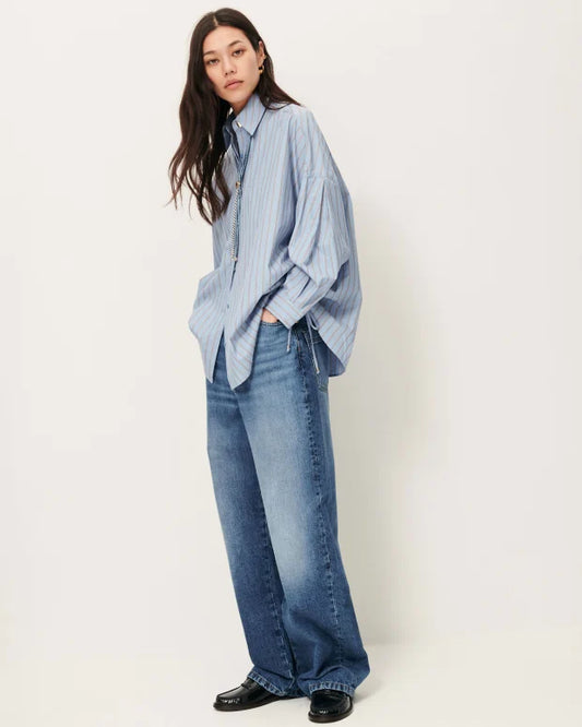 Person wearing a light blue shirt and jeans on a white background