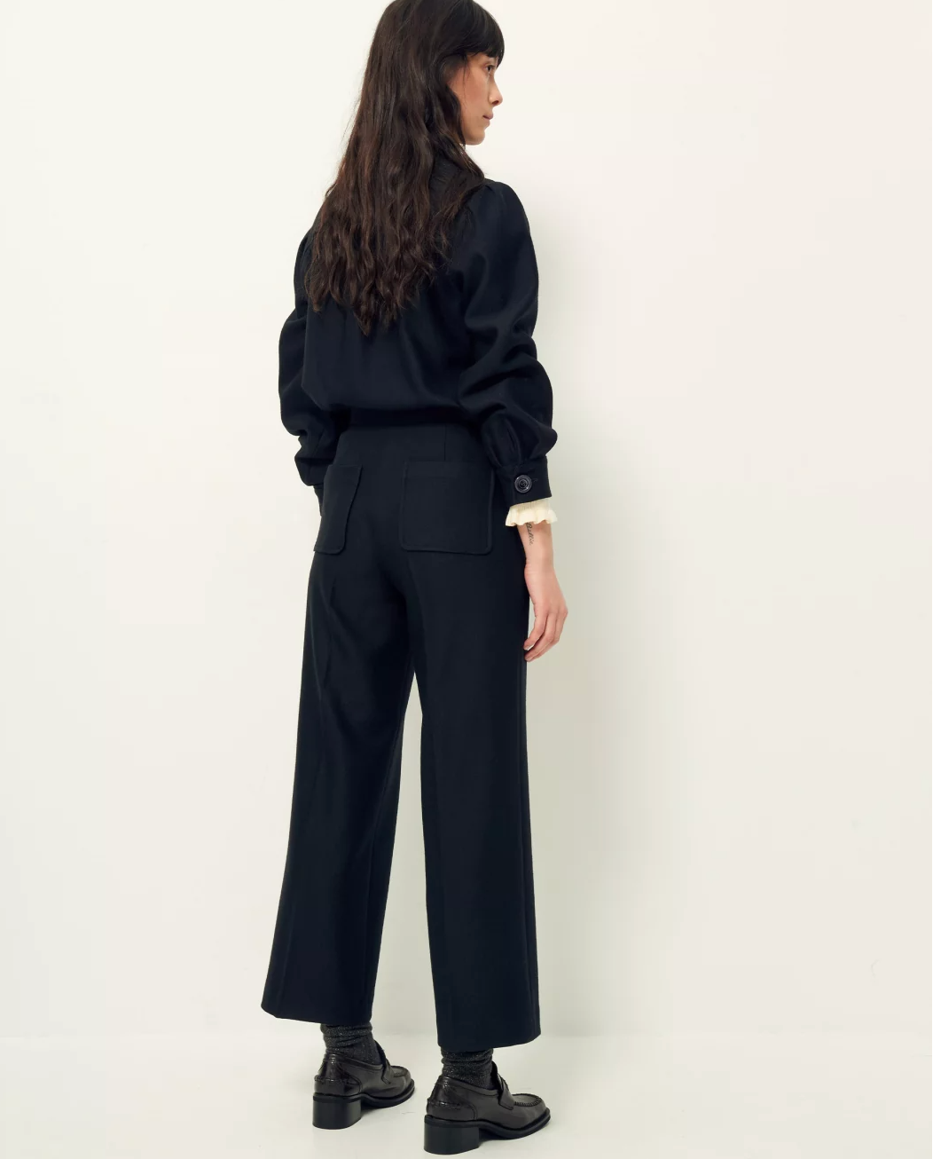 Back view of woman wearing wide leg black wool pants.