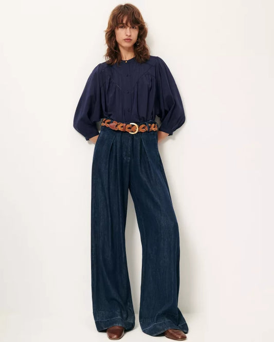 Person wearing a navy blue outfit with wide-leg pants and a belt on a white background