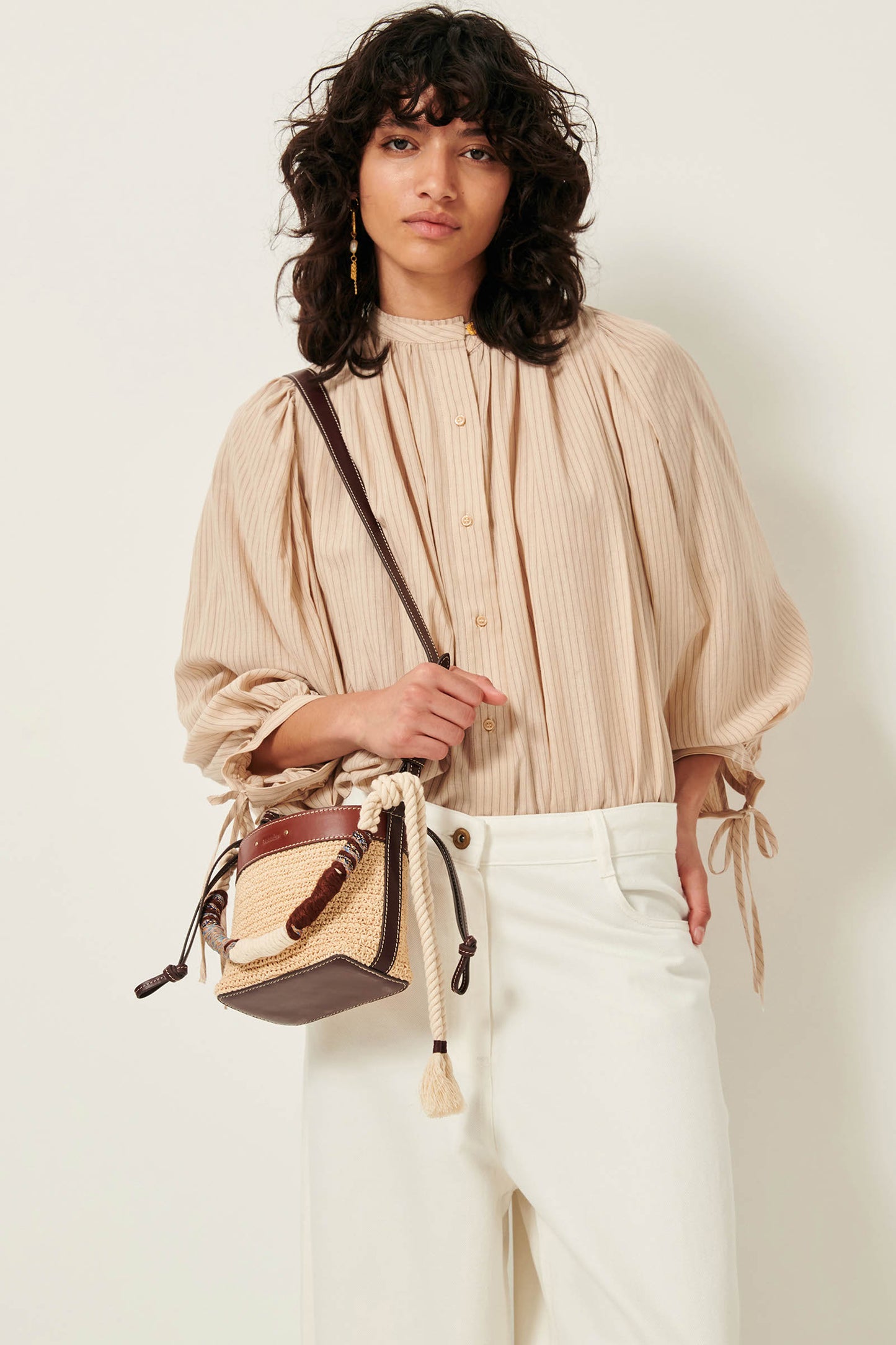 Picture of wavy brown haired young woman with brown eyes wearing a light brown striped shirt.