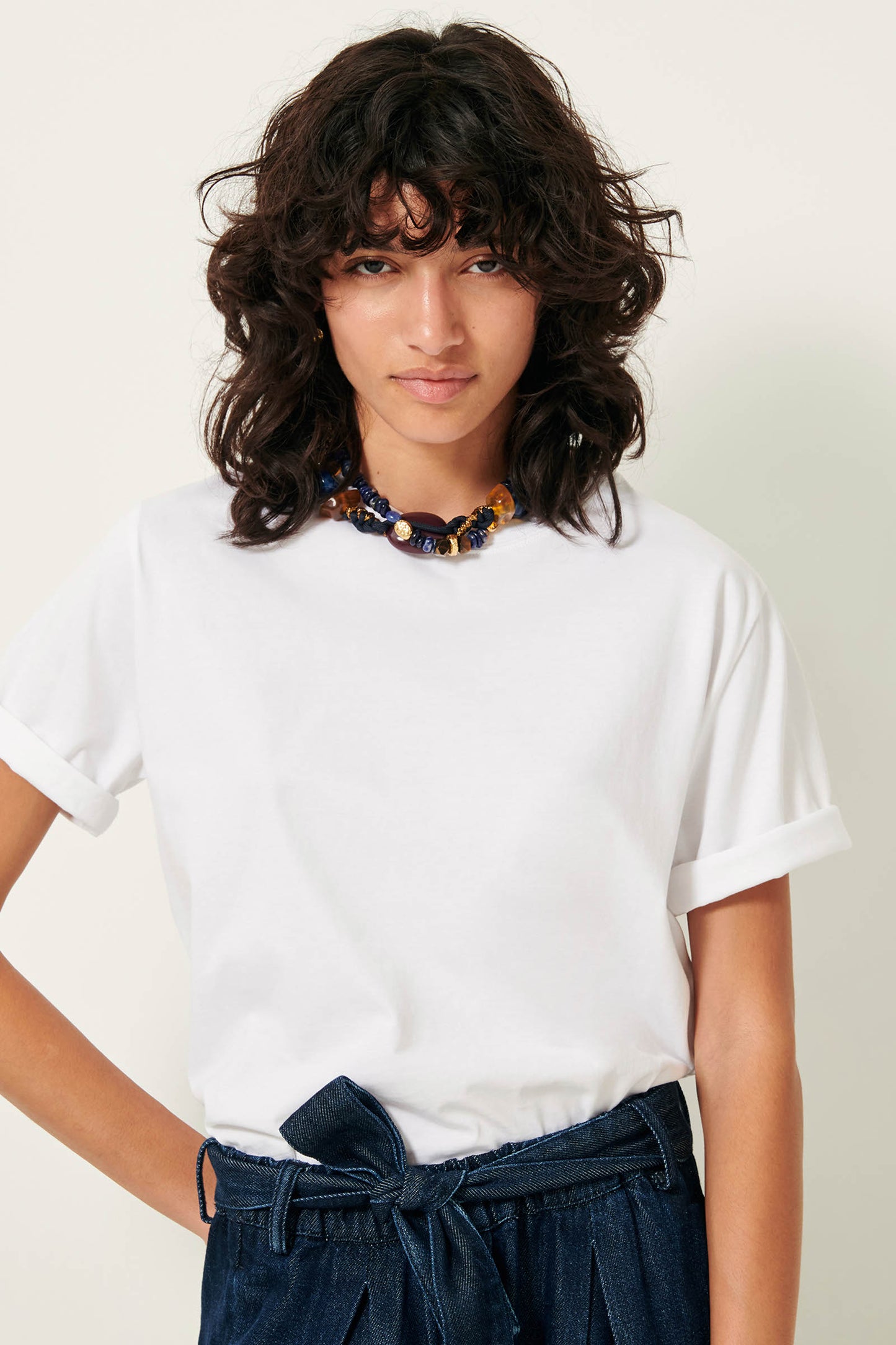 Picture of Brown wavy haired young woman with brown eyes wearing a white shirt blue pants