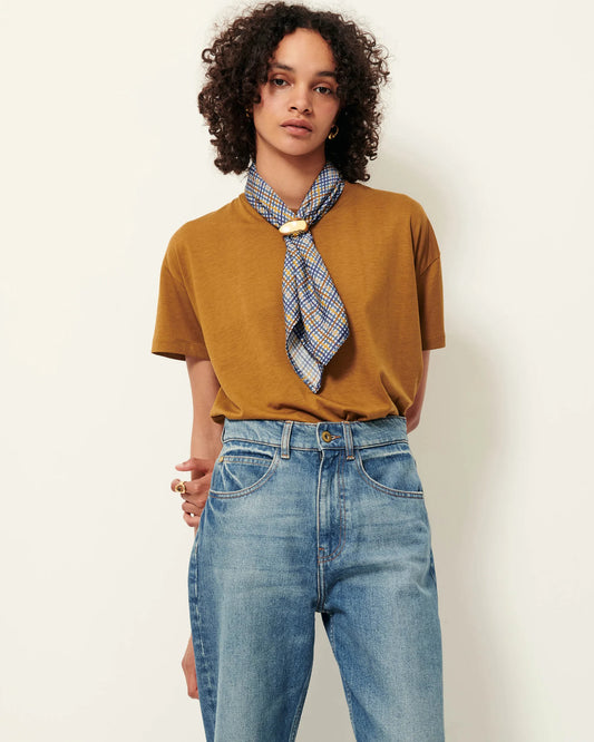 Model wearing a bronze short sleeve T-Shirt with a scarf and jeans. White background