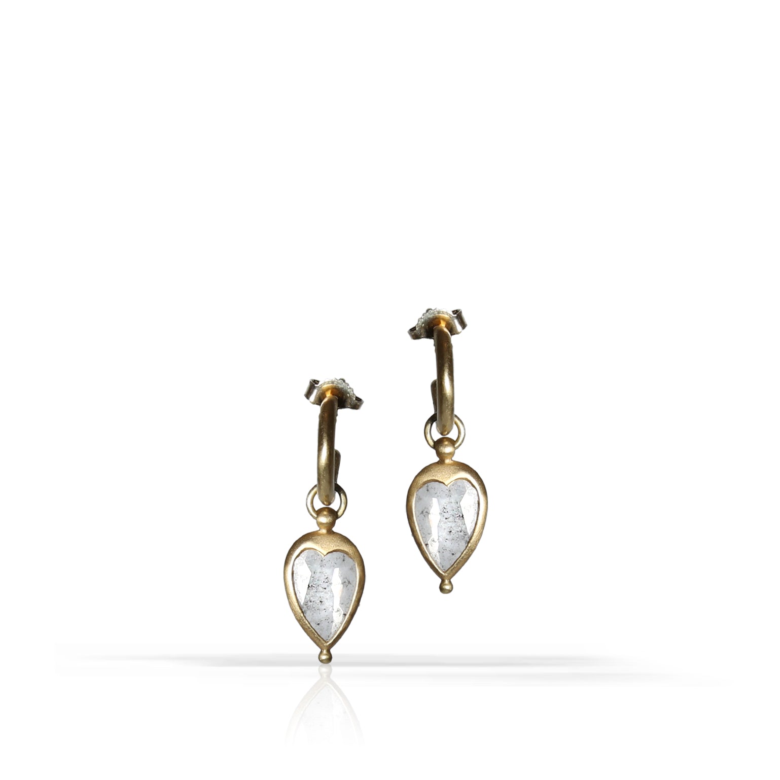 A pair of gold hoop earrings with heart-shaped diamond drops, displayed on a clean white background with a soft reflection below.