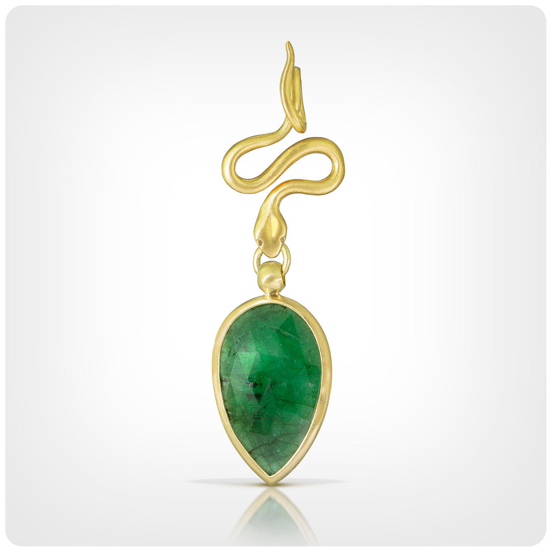 A gold pendant featuring a curved, snake-like top design and a teardrop-shaped green gemstone drop, shown on a light gray gradient background.